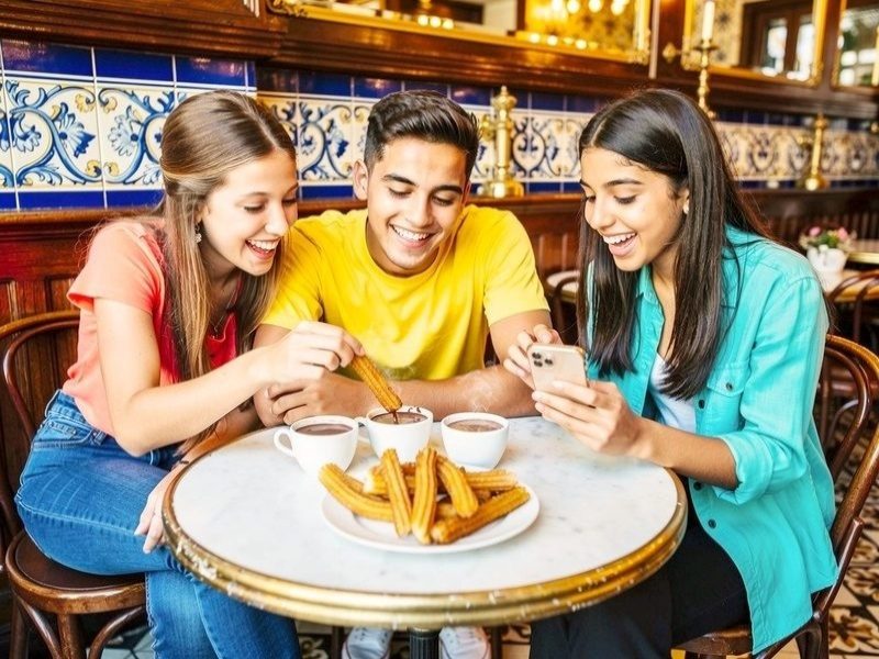 Friends sharing churros and chocolate at a tiled café in Madrid